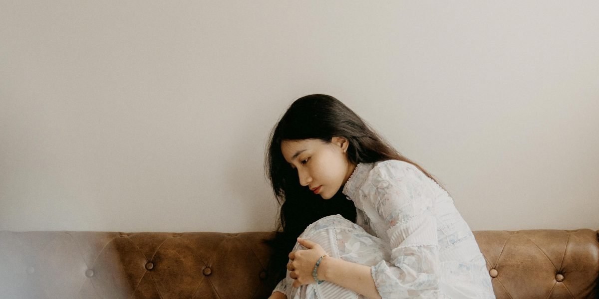 Person sitting on a couch looking reflective with a warm blanket