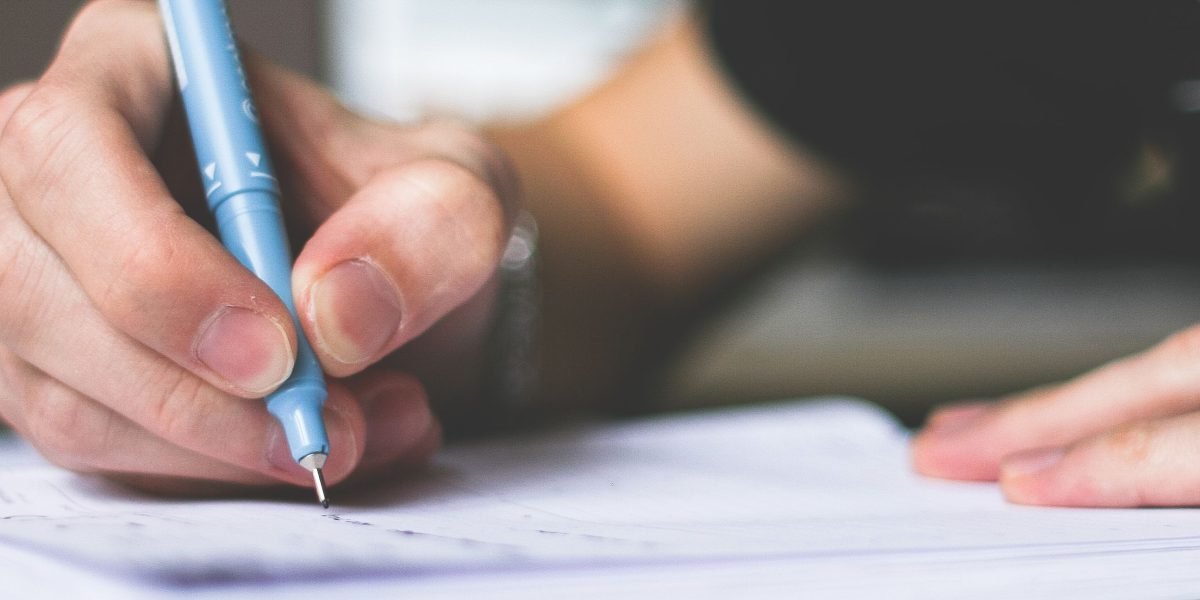 A person intently writing notes on a pad, demonstrating the process of creating a personal safety plan for challenging situations.